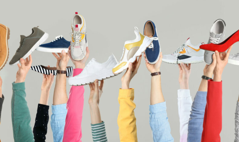 Set of people holding different stylish shoes on color background, closeup