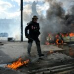 Policier anti-émeute devant une voiture en feu, place de la République à Paris