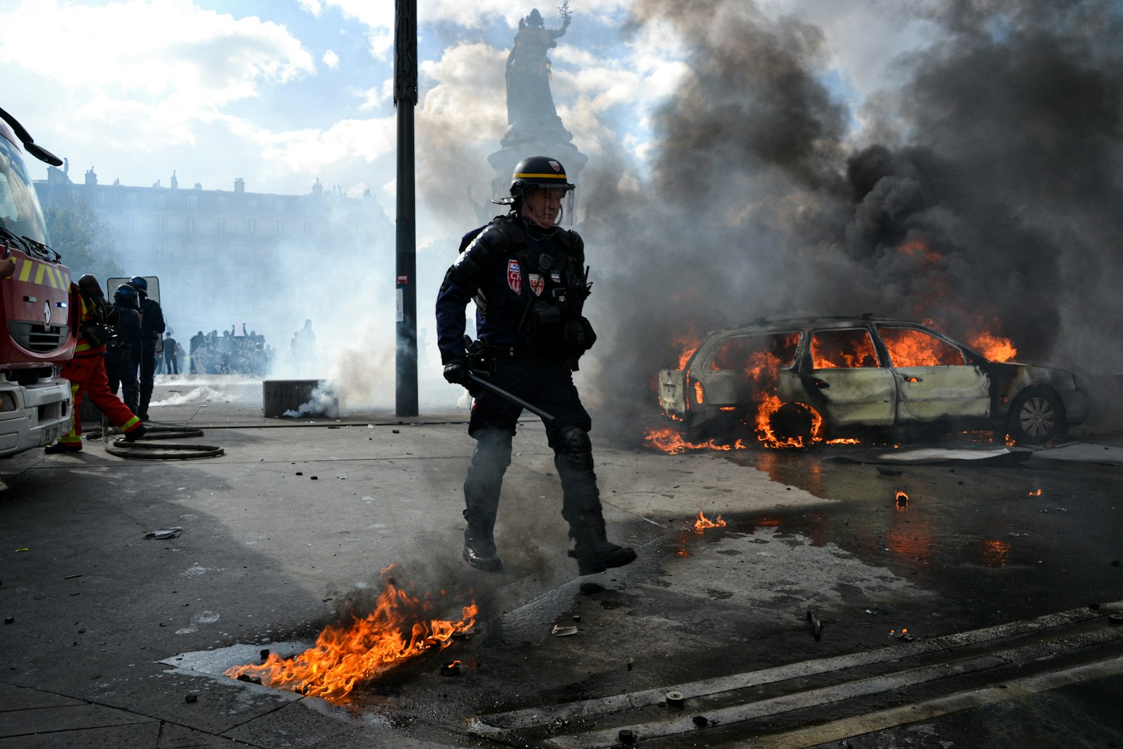 Policier anti-émeute devant une voiture en feu, place de la République à Paris